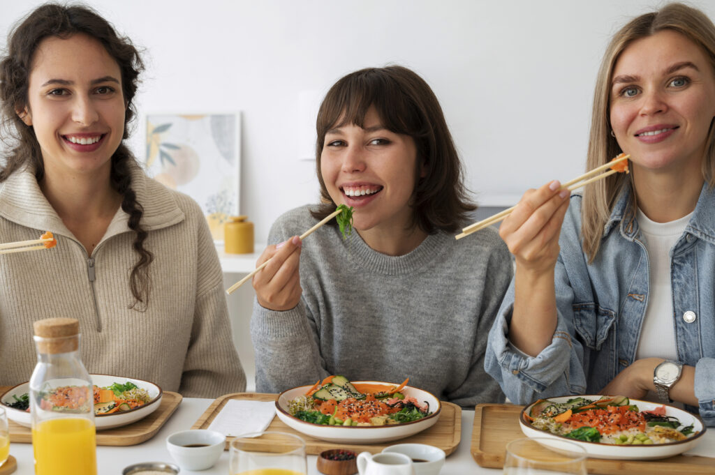 female friends eating seafood dish with salmon together